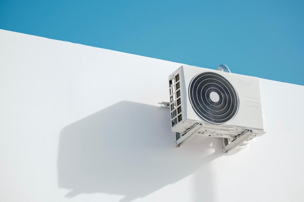 Unité extérieure de climatisation fixée à un mur blanc